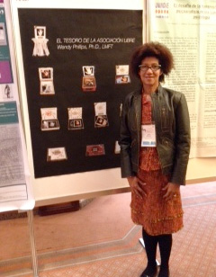 Wendy Phillips stands next to a sign that reads "El Tesoro de la Asocicion Libre"
