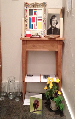 Art installation called "The Colors of Grief" that includes a photograph, flowers, cards and framed abstract image